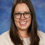 A woman with long brown hair and glasses smiles against a blue and purple background.