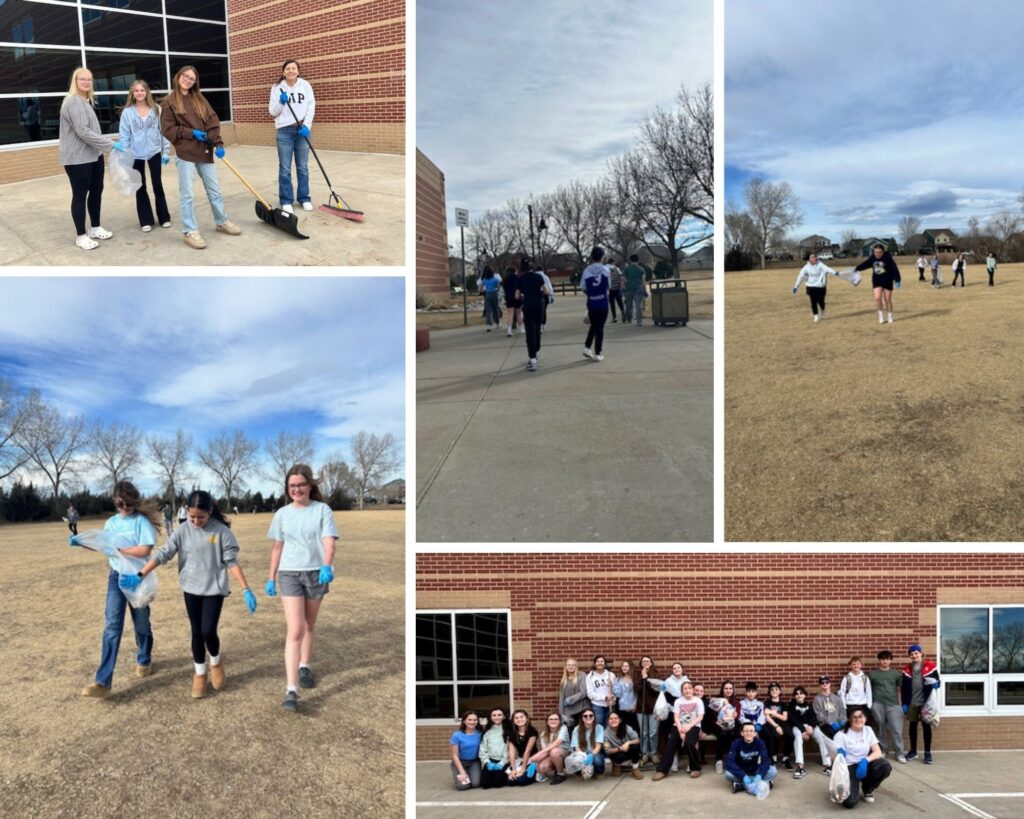 Students participate in a community cleanup, collecting trash and walking outdoors on a sunny day.